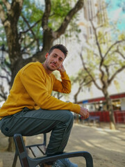 Obraz premium Man sitting on a bench in the park dressed in autumnal clothes.