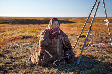 The extreme north, Yamal, life of Nenets people, reindeer herder's assistant, woman sitting on the ground waiting