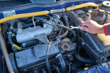 man tries to repair a broken car