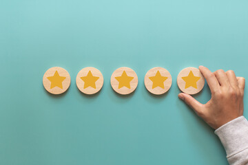Hand of client giving a five star rating. Customer putting wood cube star shape for rating or...