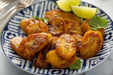 Fried caramelized plantains served with lime wedges and cilantro © fahrwasser