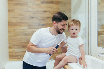 man father teaches his son the boy in the bathroom brushing teeth, happy