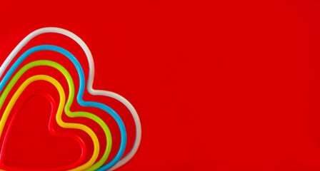 stack of multicolored hearts on red background