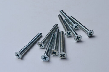 metal screws with a cross-head screwdriver slot lie on a light background. close-up.