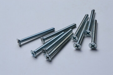 metal screws with a cross-head screwdriver slot lie on a light background. close-up.