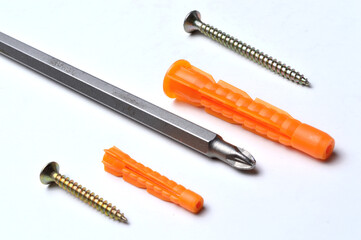 plastic dowel, screwdriver and several screws on a light background. close-up.