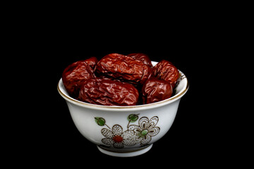 Dried Red Date Jujube in a Ceramic Chinese Tea Cup isolated on black background. Selective focus.