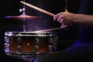Drummer playing snare drum with sticks close up.