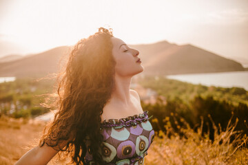 Lifestyle shot of curly hair girl enjoying the sunlight in summer