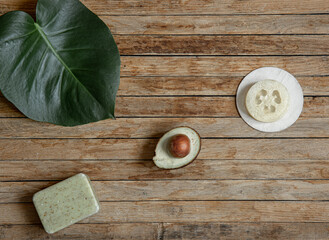 Fototapeta na wymiar Spa composition with natural soap, avocado and loofah on a wooden surface top view.