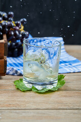 A glass of white wine on a wooden table with grapes