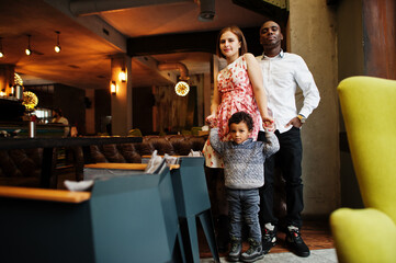 Happy multiethnic family with boy kid spend time at restaurant. Relationships of african man and white european woman.