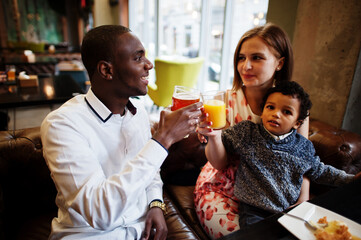 Happy multiethnic family with boy kid spend time at restaurant. Relationships of african man and white european woman.