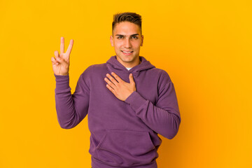 Young handsome caucasian man isolated taking an oath, putting hand on chest.