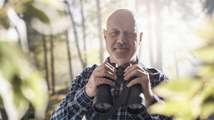 Tourist walking in a forest and using binoculars