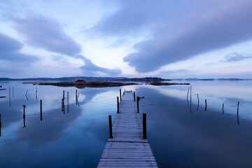 Obraz premium Beautiful seascape with bridge, rocky islands, and magenta clouds in a symmetrical composition on an early morning in Sweden
