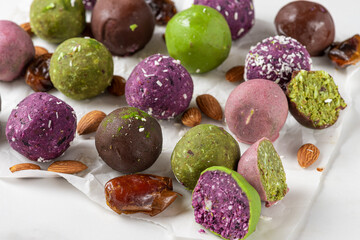 Raw vegan desserts. Energy balls. Various colorful bliss balls in chocolate glaze on white background.