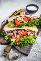 Pita sandwich with roasted chicken, vegetables and delicious sauce. White background. Top view