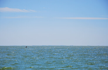Fototapeta premium Blue sea and sky, silhouette of fishermen with his boat, small fishing boat in beautiful blue sea water