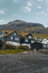 Fototapeta na wymiar Bour village Grass-covered picturesque houses at the Faroese coastline in the village Bour with view onto Dranganir and Tindholmur during spring.