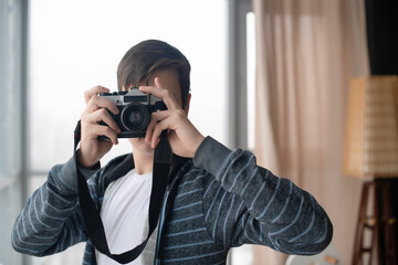 A young man takes a photo with a retro camera in the studio.