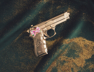 Gold glitter ans golden gun with pink bow tie on green fabric. Flat lay