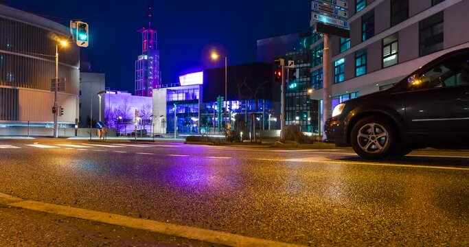 Timelapse of traffic with light trails of cars and city lights at night on a wet road.