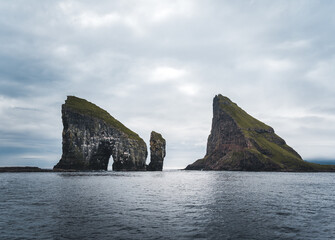 Close-up shot of famous Drangarnir cliff with Tindholmur islands in the background taken during early morning hike in spring at Faroese coastline Faroe Island, Denmark, Europe