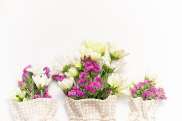 Pink statice and white chrysanthemum flowers on a white background. Top view. Copy space. Space for the text. The concept of the holiday.