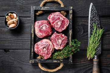 Raw lamb neck meat on a butcher table with knife. Black wooden background. Top view