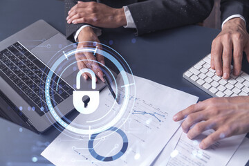 Two businesspeople man and woman working on the project to protect cyber security of international company. Padlock Hologram icons over the table with documents. Formal wear. Workspace.