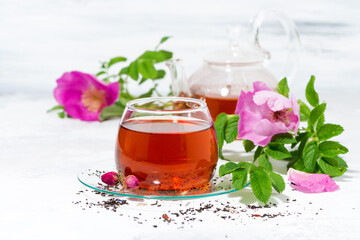 tea with wild rose in a glass cup on a white background