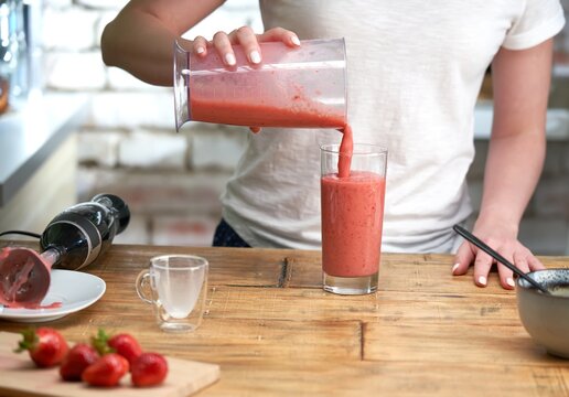 Woman making strawberry smoothie. Healthy eating, cooking and summer refreshment concepts.