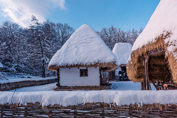 Traditional Romanian village in Transylvania with old house straw roofing covered with snow in a...