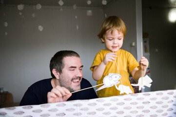 Father and son play in the puppet theater at home.
