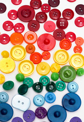 Group of plastic colorful buttons on white background. Rainbow colors red, orange, yellow, green and blue tailor texture