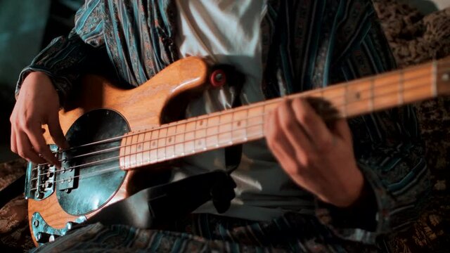 Man plays the bass guitar while shifting focus