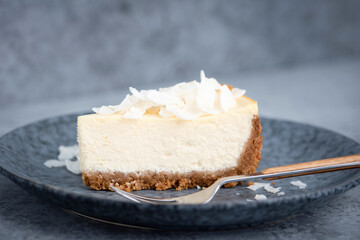 Slice of coconut cheesecake on blue plate. Delicious cake slice