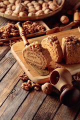Walnut cake, nuts and wooden kitchen utensils on a wooden table.