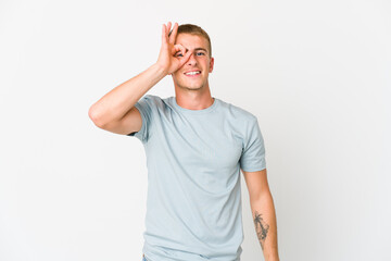 Fototapeta premium Young caucasian handsome man excited keeping ok gesture on eye.