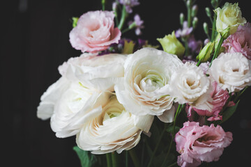 Beautiful bouquet of flowers with white ranunculus. Wedding bouquet on black background, closeup view, soft tones