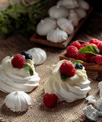 Dessert Pavlova and small meringues on a rustic background.
