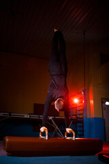 Adult man in sportswear doing exercises on gymnastic apparatus in the acrobatic gym