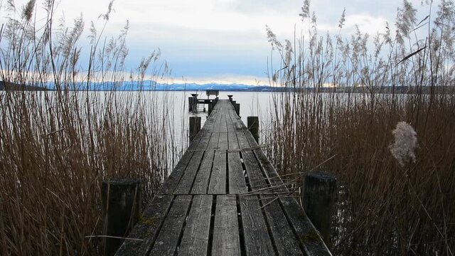 Old wooden dock in a mountain lake. Old wooden jetty surrounded by moving reeds in a mountain lake.