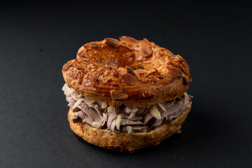 Round eclair with buttercream and nuts, beautiful photo on dark background