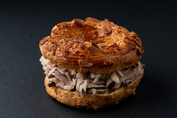 Round eclair with buttercream and nuts, beautiful photo on dark background