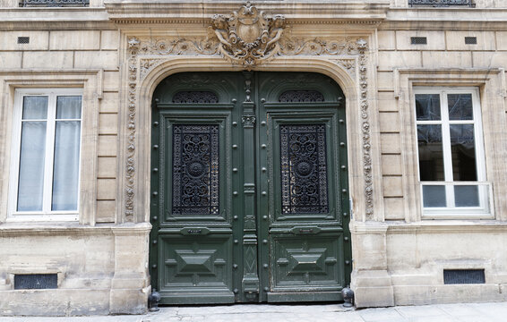 Classical architecture entrance with door painted in green color and golden plates on door panels. Facade of house in Paris France