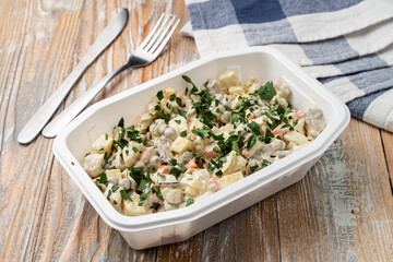Food delivery: russian salad with  in a plastic box with no lid