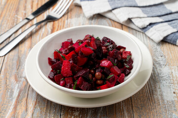 Ukrainian salad made of boiled vegetables in a white bowl on a rustic wooden table