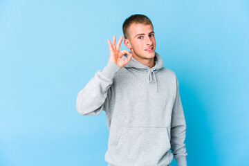Young caucasian handsome man cheerful and confident showing ok gesture.